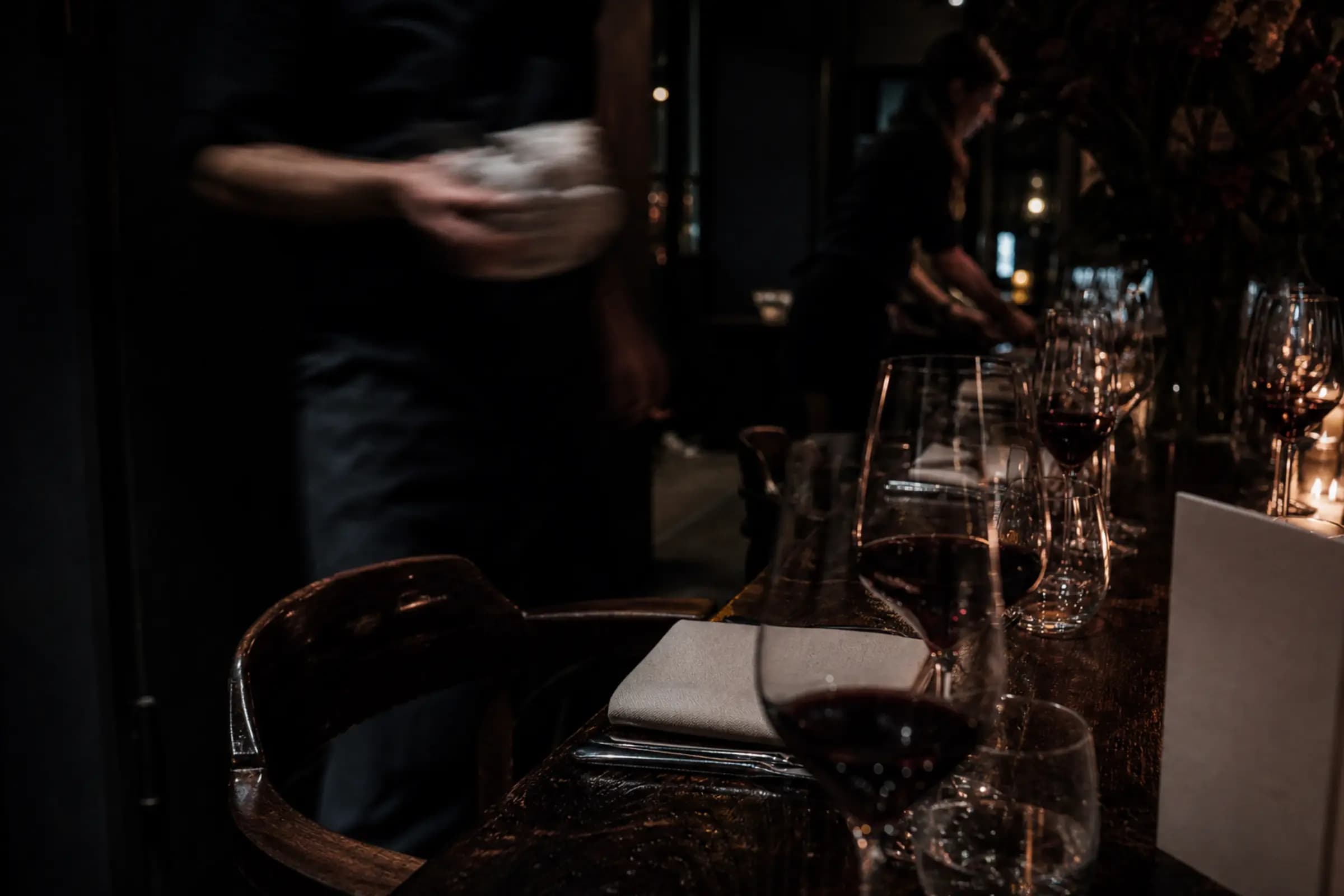 Dunkler Eventraum mit gedecktem Tisch und Servicebewegung