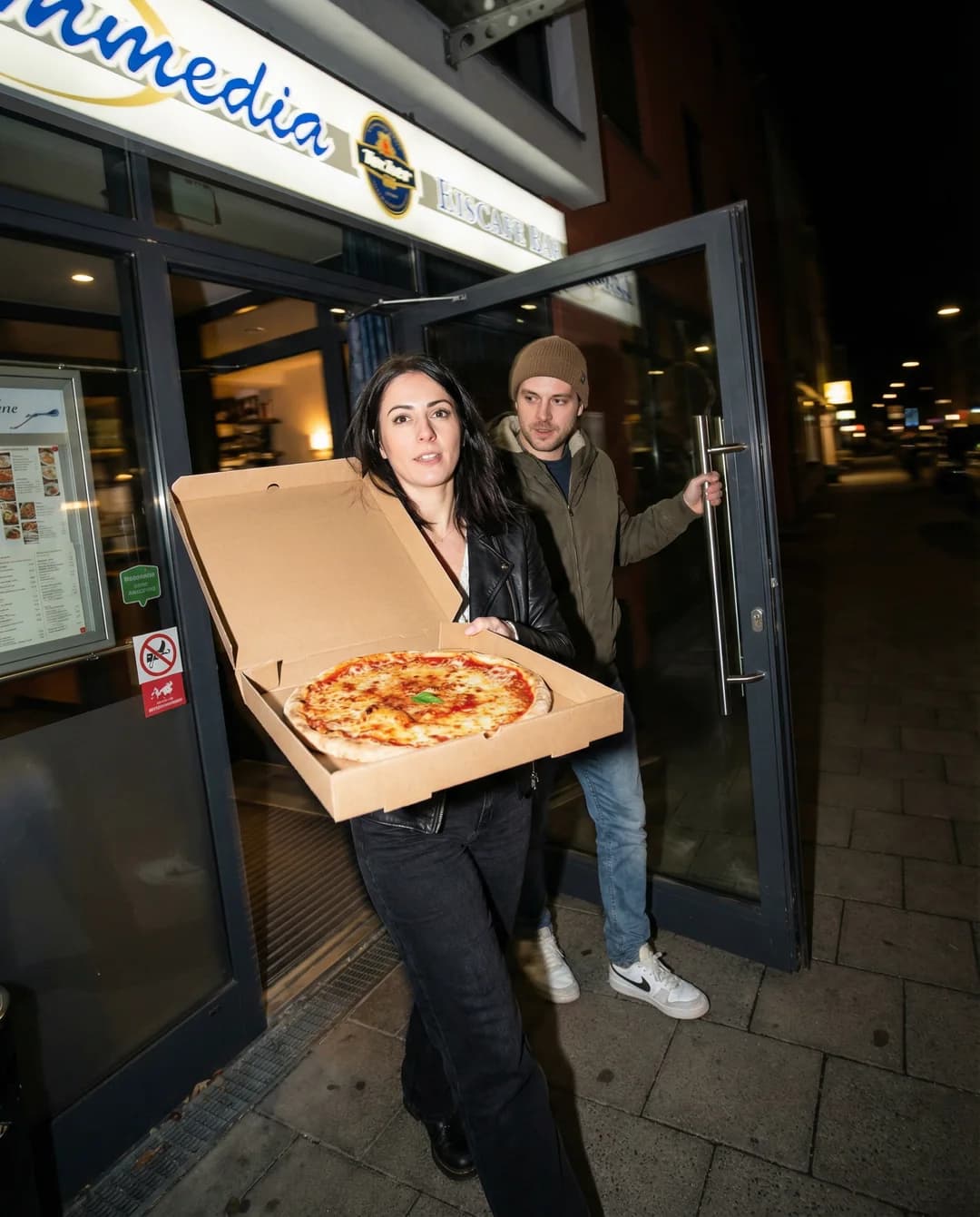 La-Commedia-Motiv mit Gästen, die eine Pizza zum Mitnehmen abholen
